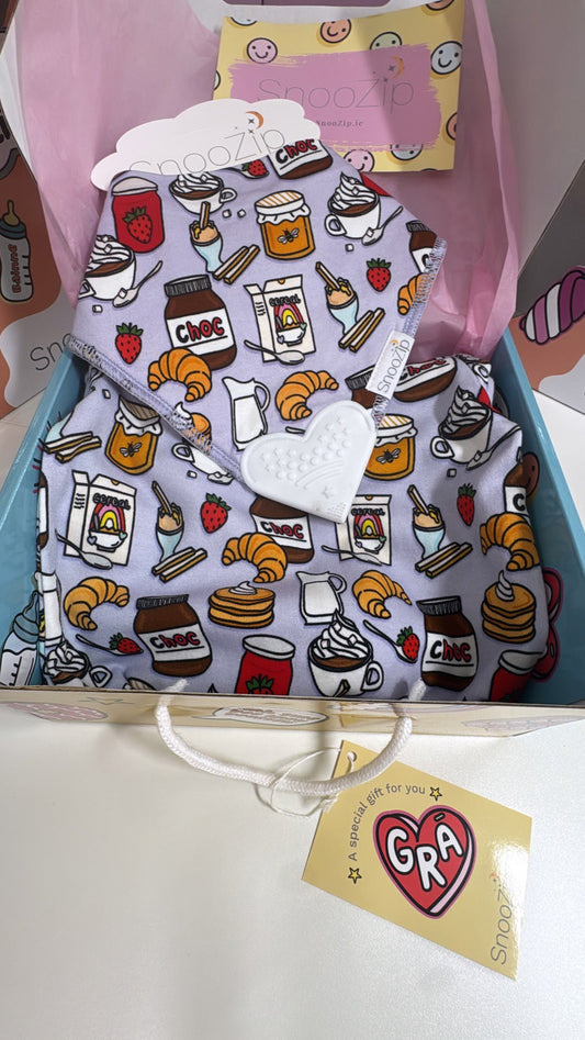 Baby bib with food-themed design in a box with a visible brand tag.